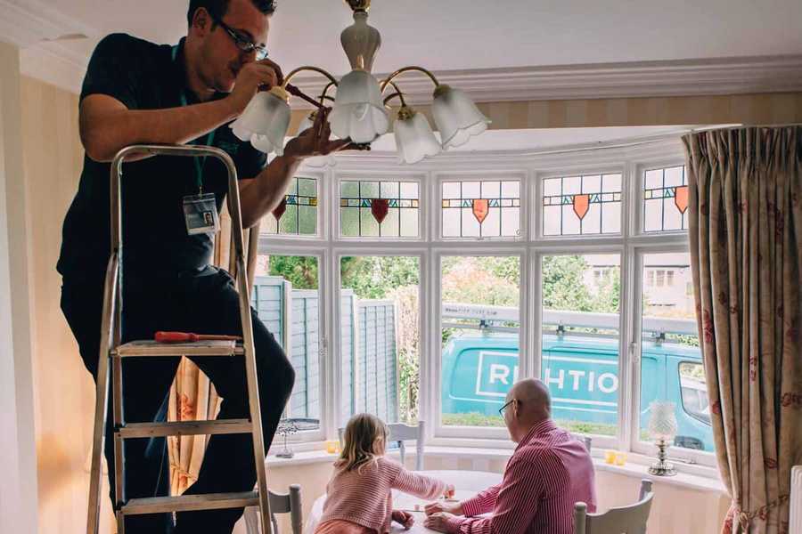 Engineer Checking Light Fittings in Living Room