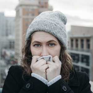 Woman outside Wearing Hat and Blowing on Hands