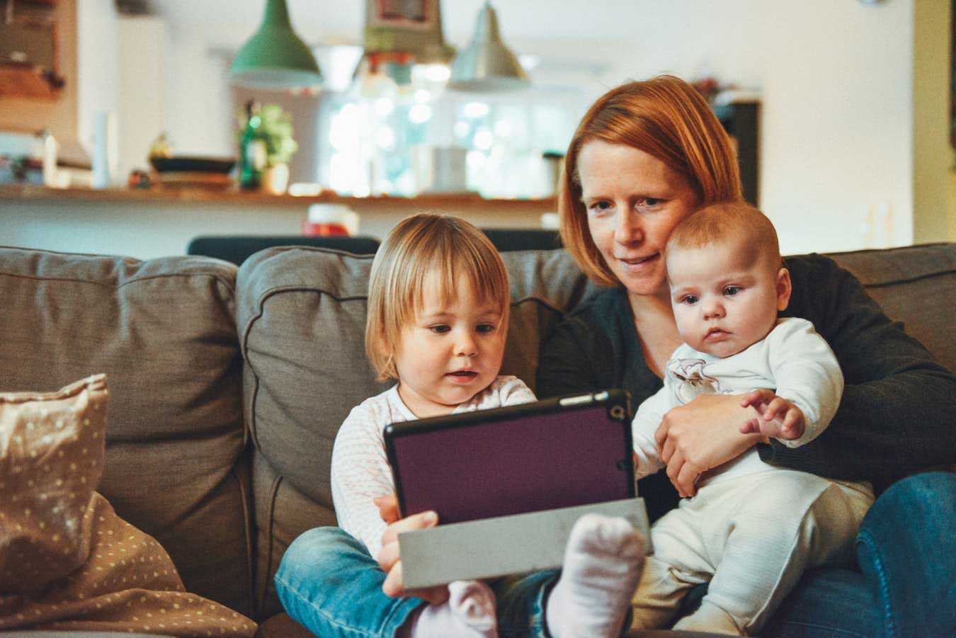 Mother and Two Children Staring at Tablet while on Sofa