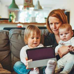 Mother and Two Children Staring at Tablet while on Sofa
