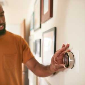 a man adjusting his thermostat