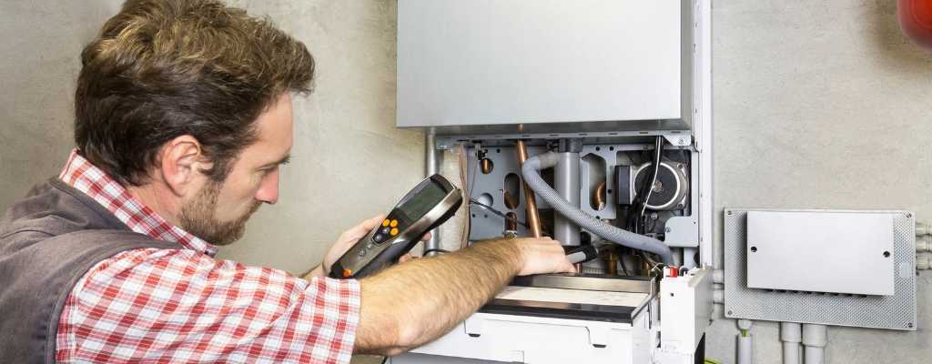 a male plumber assessing the inside of a boiler