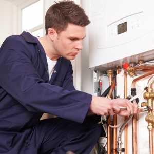 a male engineer fixing the pipes attached to the boiler