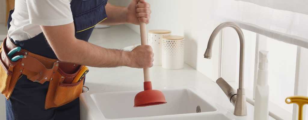 plumber using a plunger in a sink