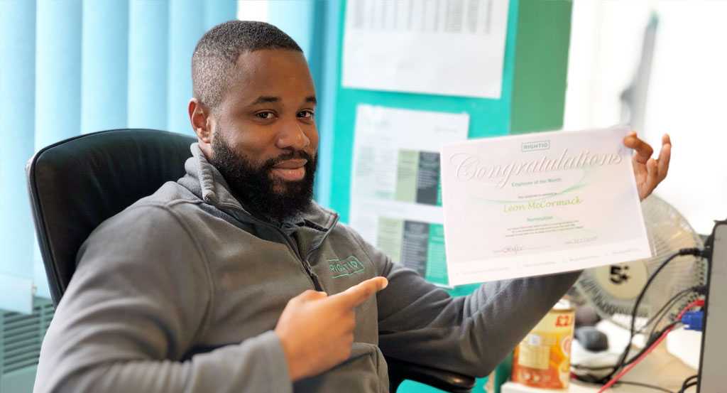 Leon Mccormack Pointing to His Employee of The Month Certificate