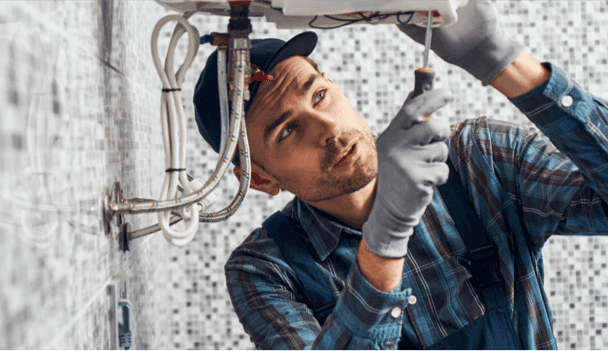 Plumber under The Boiler Fixing with A Screwdriver