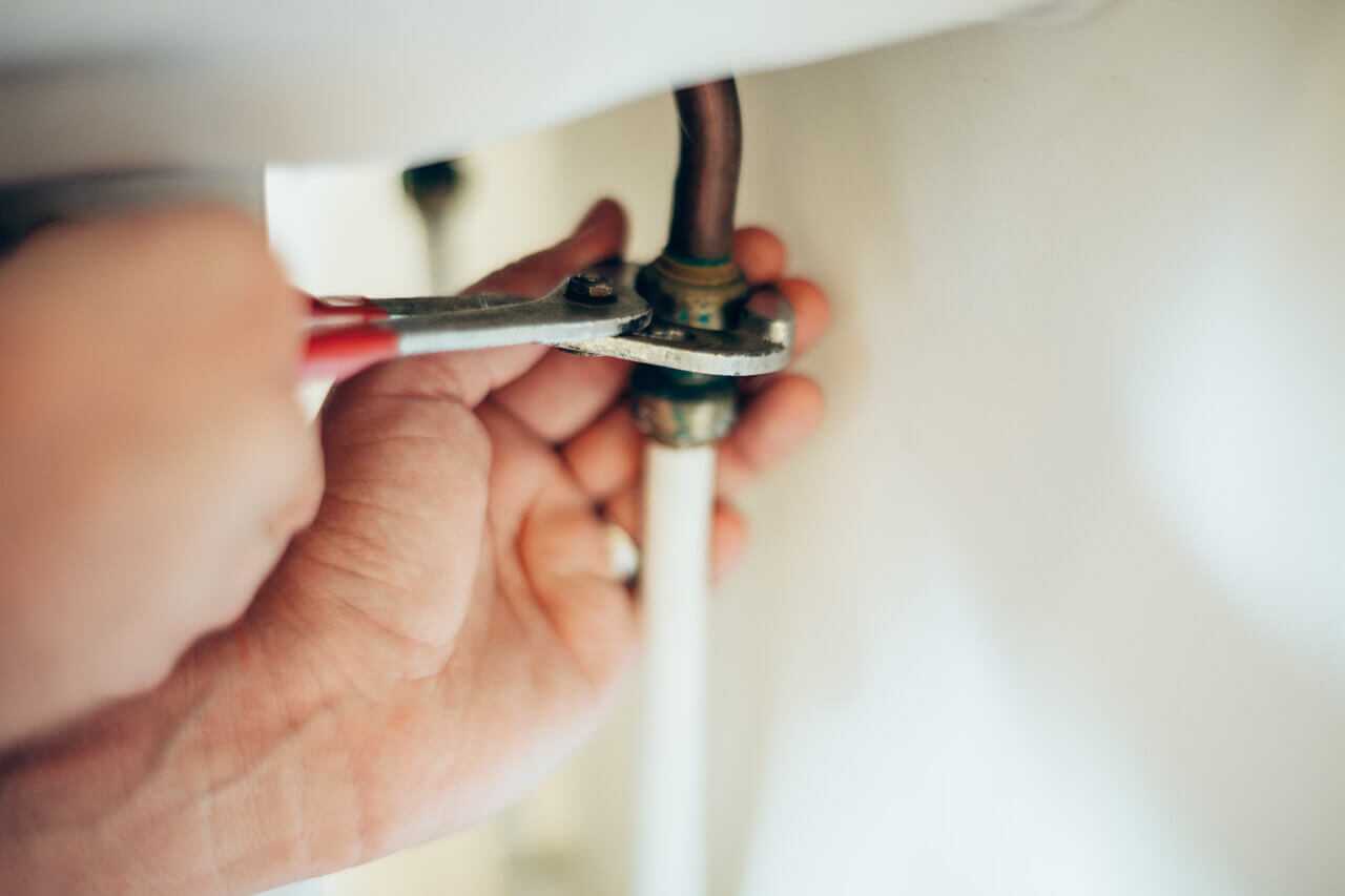 Hands with Wrench Tightening Fitting underneath Sink