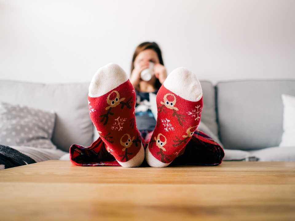 Woman on Sofa Drinking from Mug Wearing Winter Socks