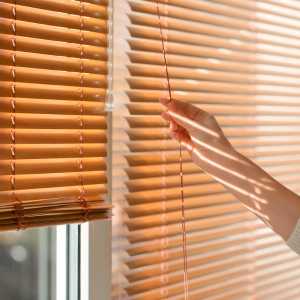 a persons hand pulling down their blinds
