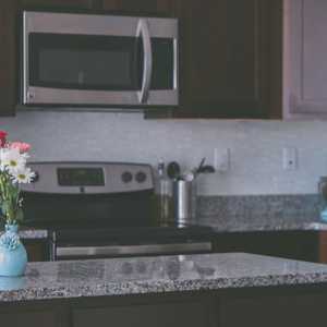 Brown and Granite Kitchen with Oven Microwave and Flowers