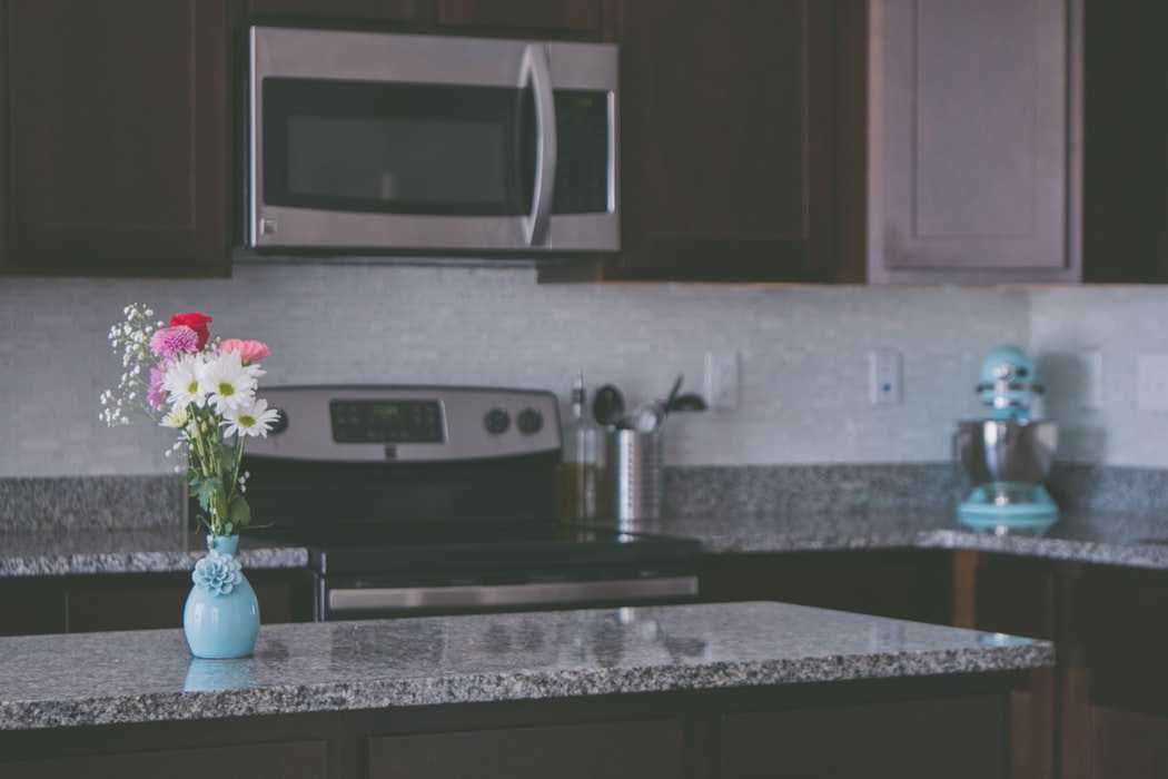 Brown and Granite Kitchen with Oven Microwave and Flowers