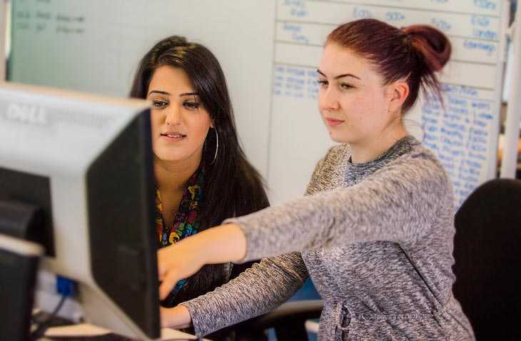 Two Women Looking  and Pointing at a Computer Monitor
