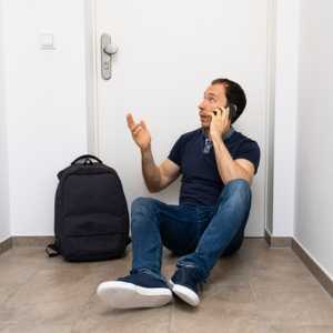 a man sitting infront of a locked door on the phone